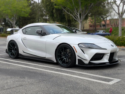 A white Toyota Supra with black aftermarket wheels, ART front lip spoiler, side skirts and a rear wing/