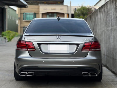 Rear view of a silver Mercedes-Benz E-Class sedan E63 style showing the rear bumper and quad exhaust outlets.